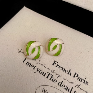 Detail of square gold earrings with white and green enamel swirl texture on retro card