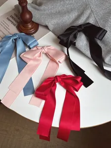 Détail de grandes barrettes à nœuds en satin avec rubans en bleu rose rouge et noir