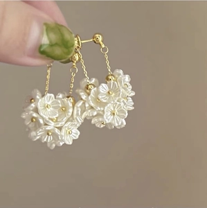 Close-up of floral pearl earrings with golden tassels and intricate cluster detail