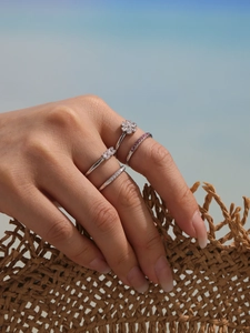 Macro shot of silver stackable rings with 5A zircons worn by a model on a beach background