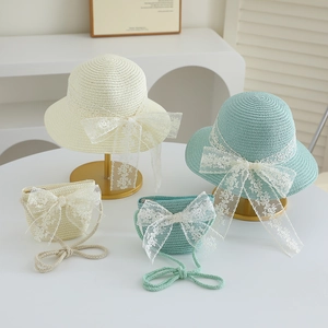 Detail of straw hat and matching bag set with large white lace bows in cream and green