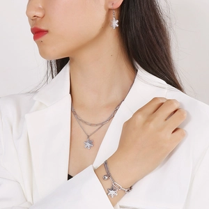 Model trägt silbernes Schneeflocken Schmuckset mit Doppelhalskette, Armband und Ohrringen