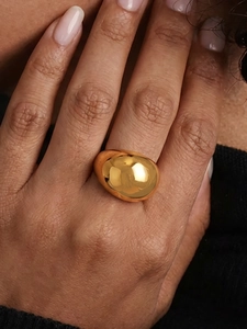 Close-up of a large polished gold geometric ring with smooth mirror finish and modern style