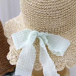 Straw sun hat with beige weave and light green checkered ribbon bow for summer beach travel