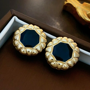 Macro shot of vintage style gold wave border earrings with black enamel center inlay