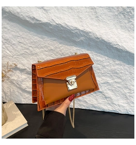 Detail of a brown and orange leather shoulder bag with crocodile texture and gold clasp