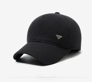 Detail shot of black knitted baseball cap featuring a triangular metal logo on side