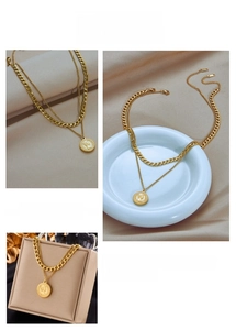 Detail of double-layer gold necklace featuring chunky cuban chain and queen coin pendant