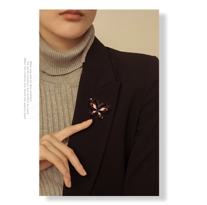 Detail of a deep purple crystal butterfly brooch on a black blazer with grey sweater
