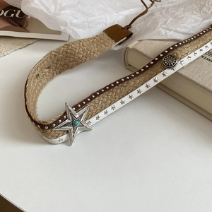 Detail of bohemian leather belt featuring star rivets, woven rope, and a turquoise stone