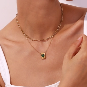 Close-up of double-layer gold chain necklace with green heart zircon pendant on neck