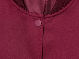 Detail of burgundy jacket showing ribbed collar and silver metal snap button closure