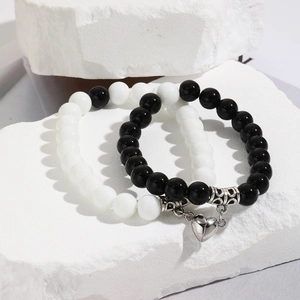 Detail of couple magnetic bracelets with black and white beads and heart charm