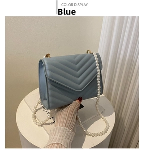 Detail of light blue crossbody bag with V-quilted faux leather and elegant pearl chain strap