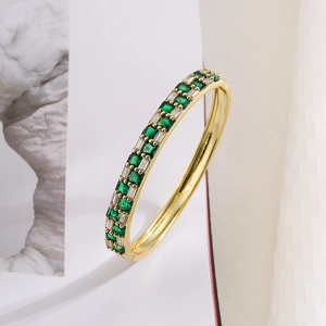 Macro shot of gold-plated geometric bracelet with green and white square-cut crystals