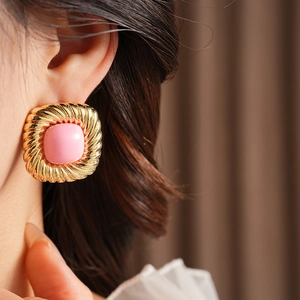 Detailansicht goldener Vintage-Ohrringe mit rosa Edelstein und gedrehtem quadratischem Rahmen