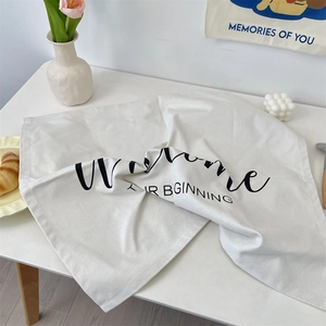 Close-up of minimalist white linen napkin with black Welcome artistic lettering on wood