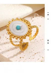 Détail d'une bague dorée vintage avec perle turquoise et incrustation spirale blanche