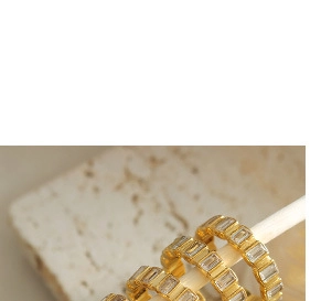 Detail of gold-plated titanium steel rings with rectangular cubic zirconia insets