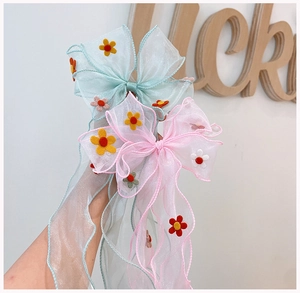 Detailed view of light blue and pink organza bow hair clips with long ribbons and small felt flowers