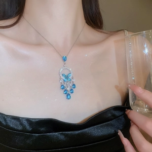 Detail of silver necklace featuring blue butterfly pendant and zircon tassel fringe