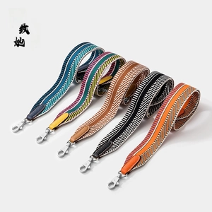 Close-up of wide adjustable woven bag straps with leather ends and metal hooks