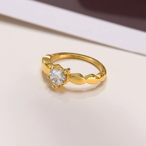 Macro detail of gold-plated heart ring featuring a zircon stone and wavy band design