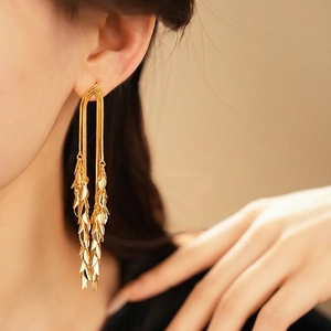Elegant gold leaf tassel earrings worn on ear showing long layered metallic chains