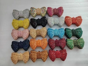 Flat lay of bow-shaped rhinestone clutch bags in various vibrant colors and metal frames