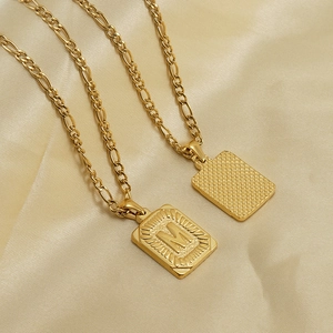 Gold 18K stainless steel Figaro chain with square letter M pendant on silk background