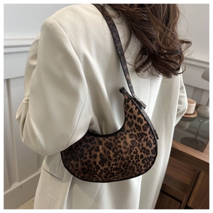 Brown leopard print saddle bag on shoulder of a model in a minimalist home setting