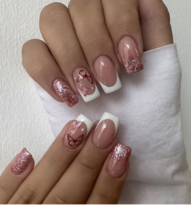 Detail of pink French press-on nails with white tips, glitter, and butterfly motifs