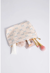 Detail of cream cotton makeup bag with blue bow pattern and cosmetic items inside
