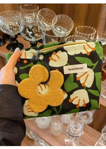 Detail of tropical plant canvas makeup bag with a plush yellow flower keychain charm