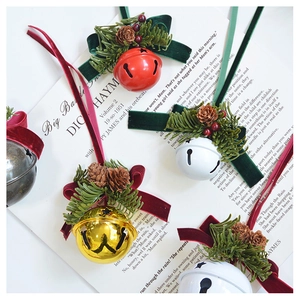 Close-up of Christmas bell ornaments with pine needles, cones and velvet ribbons