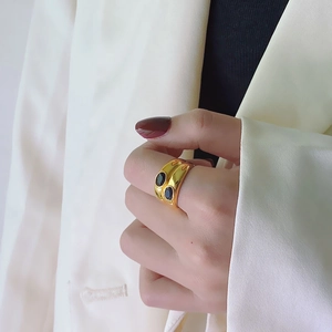 Close-up of a wide 18k gold-plated ring with two oval black zircons on a model hand