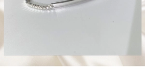Detailed close-up of polished silver square link couple bracelet on white silk fabric