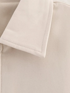 Close-up of beige twill fabric texture and high-density stitching on a baseball jacket