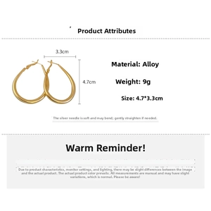 Detail view of large gold oval hoop earrings with 4.7cm height and polished alloy finish