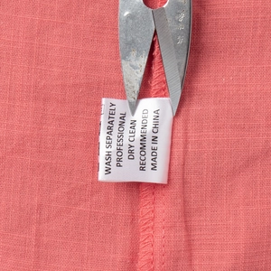 Detail of pink cotton fabric with laundry care label and washing instructions