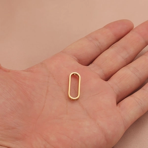 18K gold-plated oval pendant connector charm held in palm to show miniature size