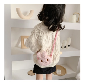 Pink plush bunny crossbody bag shown on a child wearing a white cable knit sweater