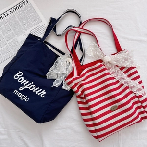 Detail of canvas tote bags with Bonjour magic text and decorative white lace bows