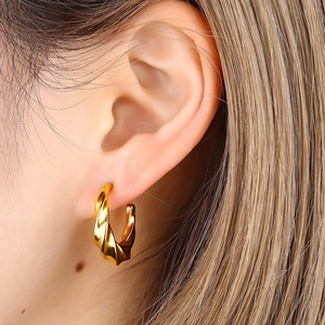 Nahaufnahme goldener gedrehter Creolen mit eleganter Spiralstruktur am Model