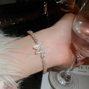 Dettaglio di un bracciale a farfalla dorato di lusso con zirconi luccicanti al polso