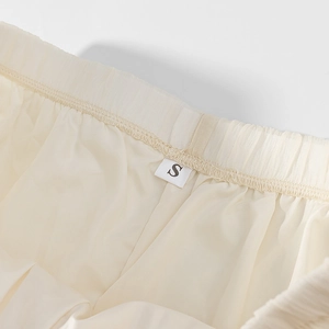 Detailed close-up of beige chiffon dress waistline with size S tag and soft pleats
