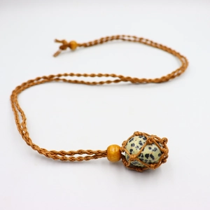 Macro detail of handmade woven net pouch necklace with a natural dalmatian stone bead