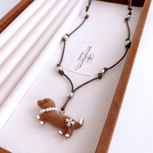 Close-up of brown flocked dachshund pendant with pearl collar on brown leather cord