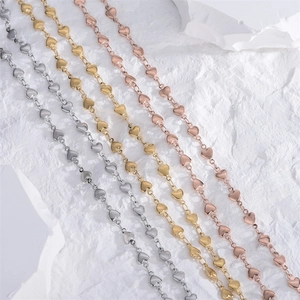 Minimalist heart chain necklaces in gold, silver, and rose gold on a stone background