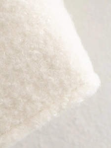 Macro shot of plush cream faux fur fabric texture for women's short cropped coat